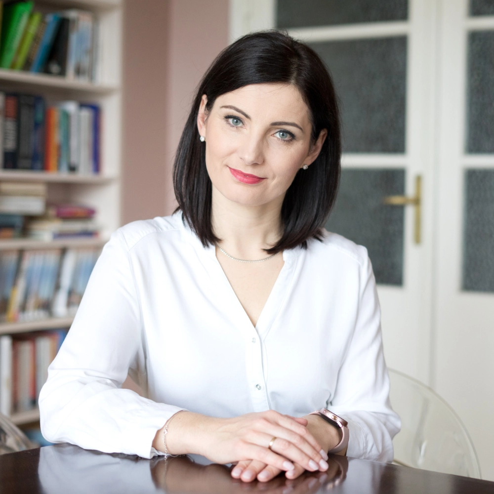 Kamila Hinc, w białej bluzce, przy stole